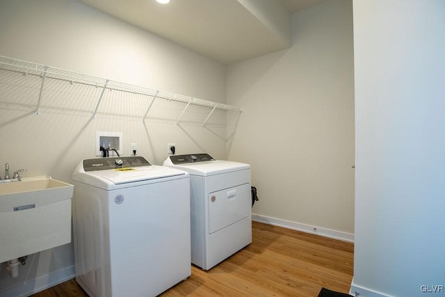 laundry room featuring laundry area, a sink, light wood-style flooring, and washing machine and clothes dryer