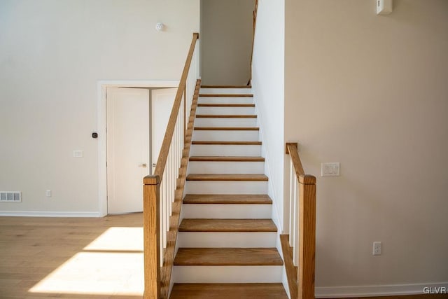 stairs with wood finished floors, visible vents, and baseboards