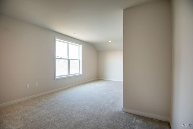 empty room with vaulted ceiling, carpet flooring, and baseboards