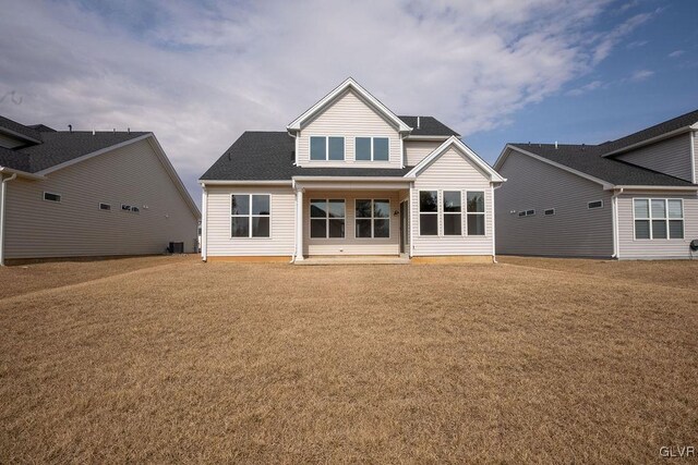 rear view of property with roof with shingles and a lawn