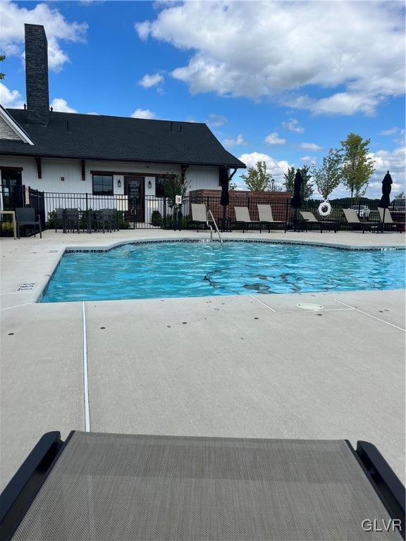 community pool featuring fence and a patio