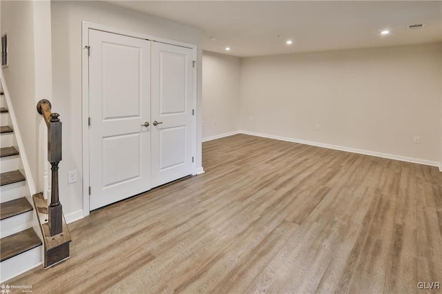 finished below grade area with visible vents, light wood-style flooring, baseboards, and stairs