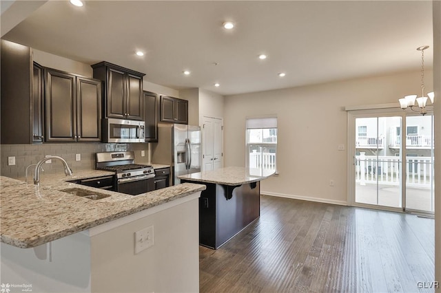 kitchen with stainless steel appliances, a breakfast bar, dark wood-type flooring, a sink, and backsplash