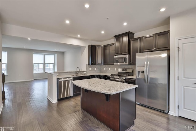 kitchen featuring dark wood-style floors, stainless steel appliances, a kitchen island, and a sink