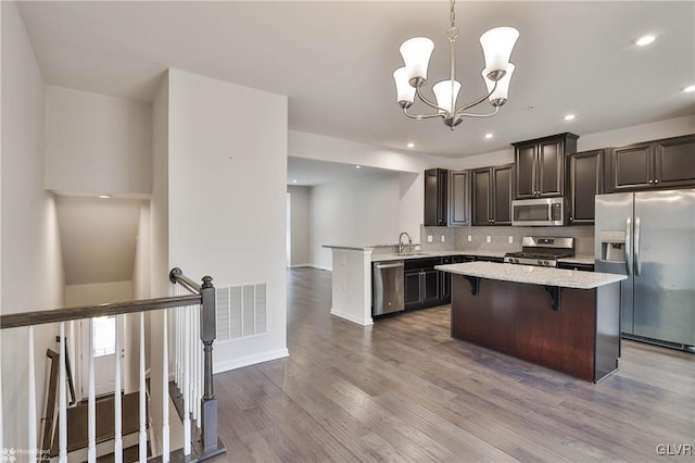 kitchen with stainless steel appliances, dark wood-style flooring, a kitchen island, visible vents, and an inviting chandelier