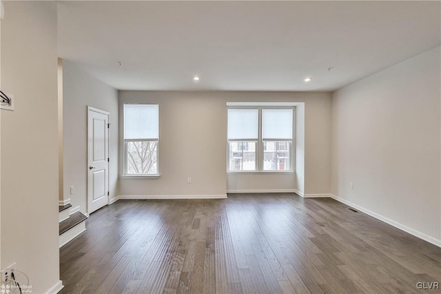 spare room featuring dark wood finished floors, plenty of natural light, baseboards, and recessed lighting