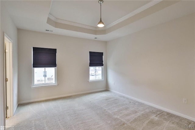 carpeted spare room featuring ornamental molding, a raised ceiling, visible vents, and baseboards