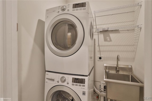 laundry area with laundry area, stacked washing maching and dryer, and a sink