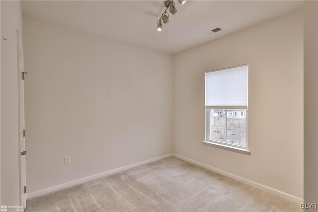 unfurnished room with rail lighting, visible vents, light carpet, and baseboards