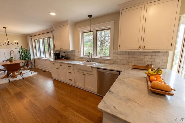 kitchen with pendant lighting, light wood finished floors, tasteful backsplash, a sink, and dishwasher