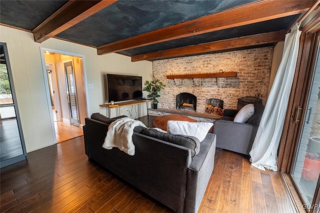 living area featuring dark wood-style floors, brick wall, a fireplace, and beam ceiling