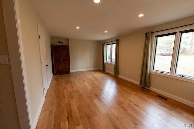 spare room featuring light wood-style flooring, visible vents, baseboards, and recessed lighting