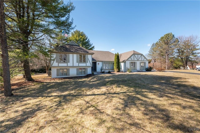 english style home with brick siding and a front yard