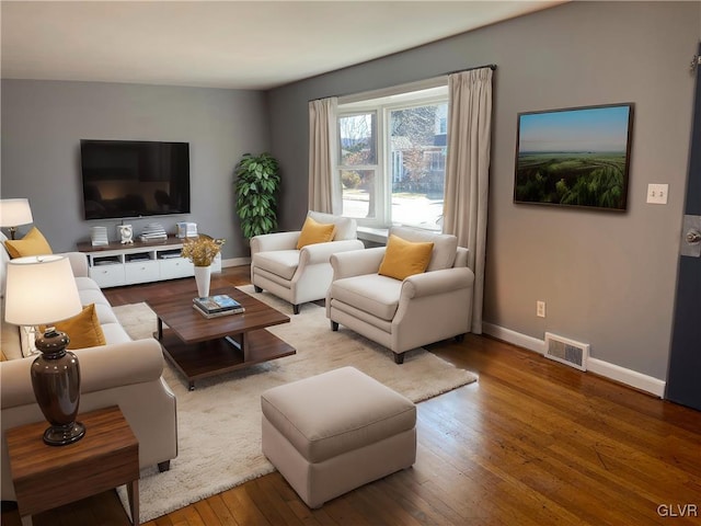 living area with wood-type flooring, visible vents, and baseboards