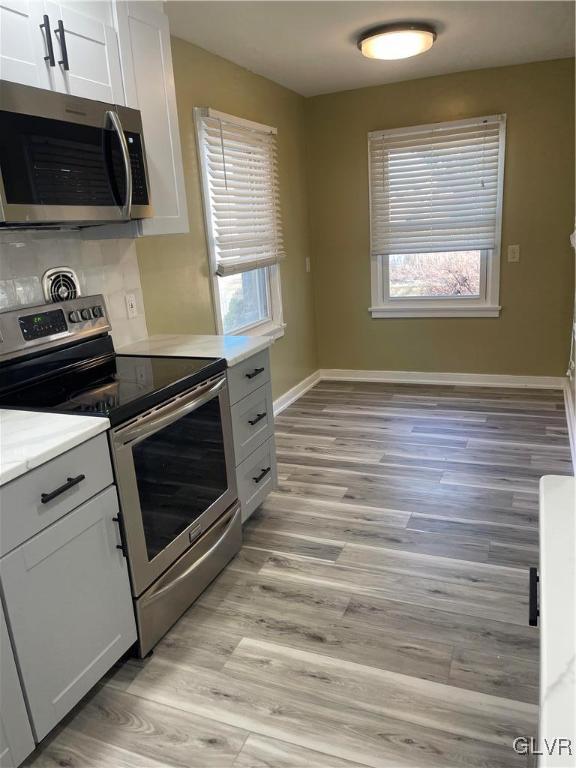 kitchen featuring light wood-style floors, baseboards, appliances with stainless steel finishes, and light countertops