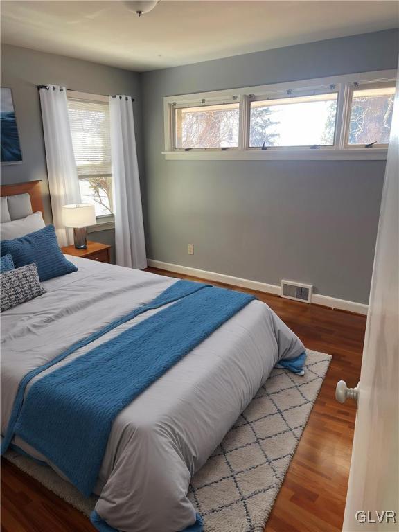 bedroom with baseboards, visible vents, and wood finished floors