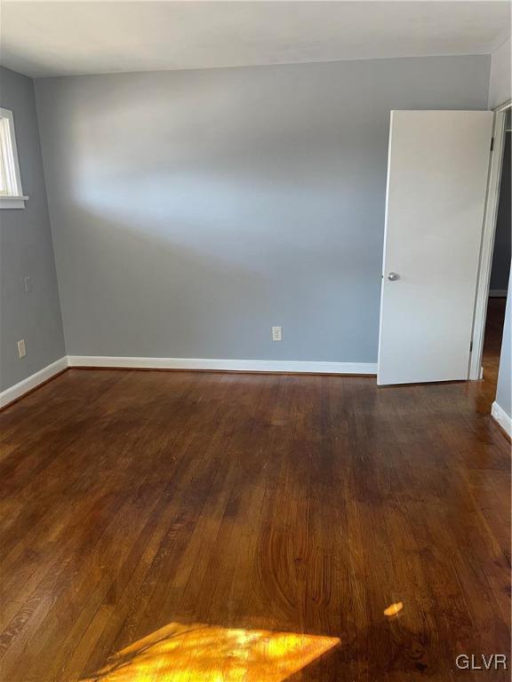 spare room with dark wood-style flooring and baseboards