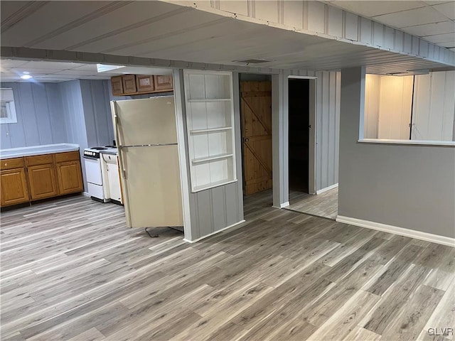 kitchen featuring light wood finished floors, a barn door, brown cabinetry, white appliances, and baseboards