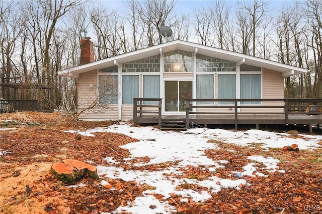 mid-century home with a deck, a sunroom, and a chimney