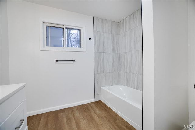 bathroom with tub / shower combination, vanity, baseboards, and wood finished floors