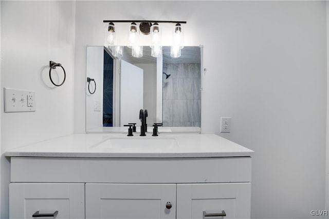 full bathroom featuring tiled shower and vanity