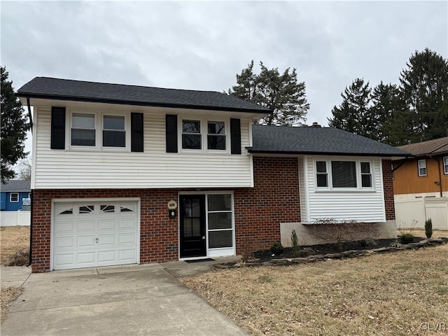 tri-level home with roof with shingles, brick siding, fence, a garage, and driveway