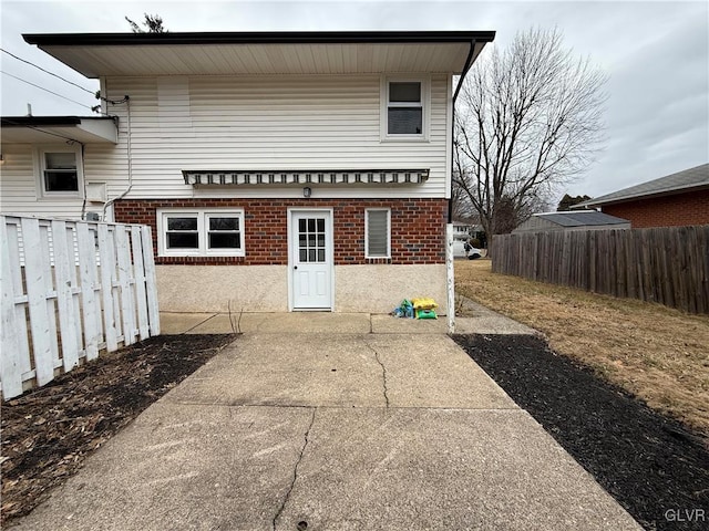 rear view of house featuring brick siding and fence