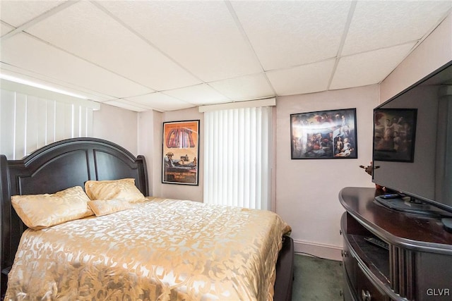 bedroom with a paneled ceiling and baseboards