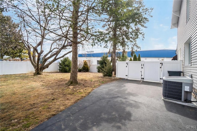 exterior space featuring central AC unit, a fenced backyard, and a gate