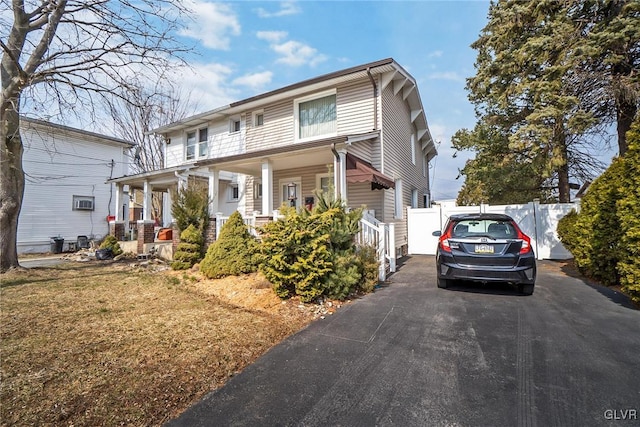 view of front of home with covered porch, driveway, and fence