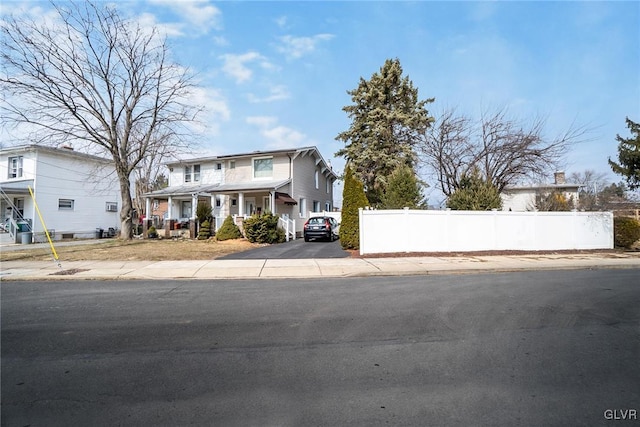 view of front of home featuring a residential view, fence, and a porch