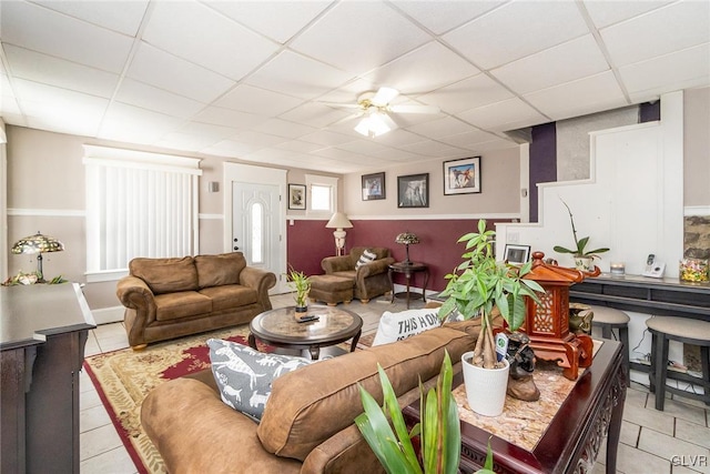 living area with a drop ceiling, ceiling fan, and light tile patterned flooring