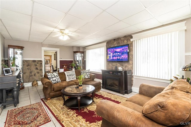 living area with wainscoting, a fireplace, tile patterned flooring, and a paneled ceiling