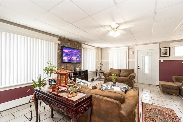 tiled living area with a ceiling fan and a drop ceiling