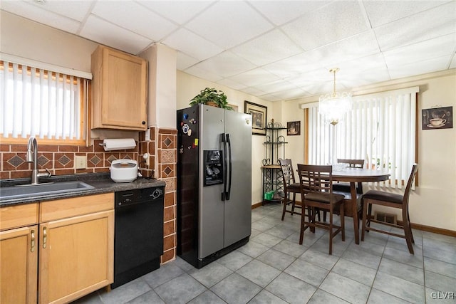 kitchen with black dishwasher, tasteful backsplash, dark countertops, a sink, and stainless steel fridge with ice dispenser