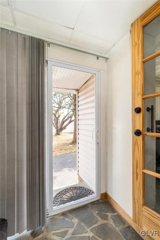 entryway featuring stone finish flooring and baseboards