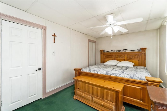 bedroom with a drop ceiling, dark carpet, and ceiling fan