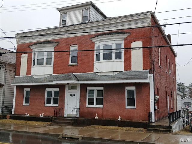 view of front of home featuring brick siding and a shingled roof