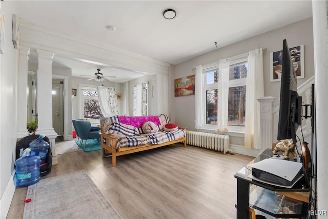 interior space featuring radiator, ceiling fan, ornate columns, and wood finished floors