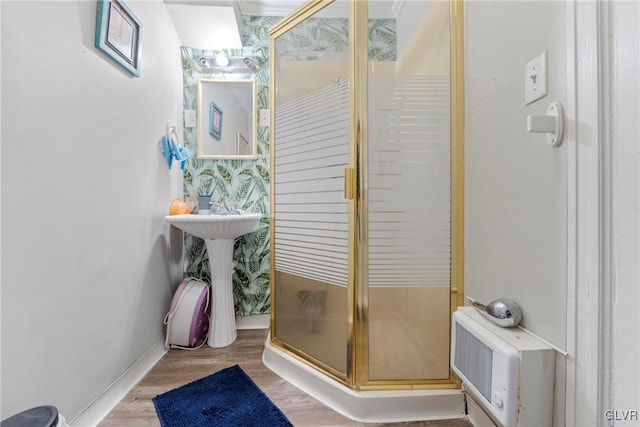 bathroom featuring wallpapered walls, a shower stall, baseboards, and wood finished floors