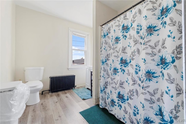 bathroom featuring a shower with curtain, wood finished floors, toilet, and radiator