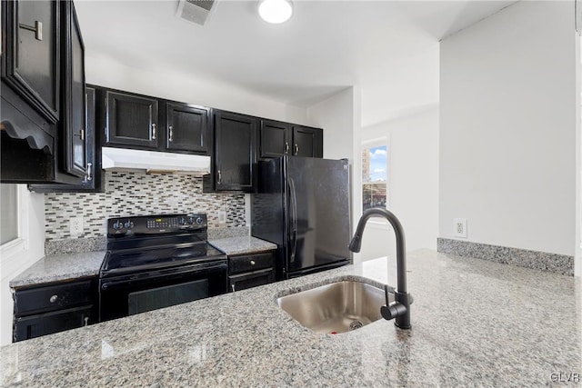 kitchen featuring dark cabinets, under cabinet range hood, a sink, backsplash, and black appliances