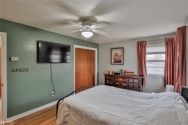 bedroom with a closet, wood finished floors, a ceiling fan, and baseboards