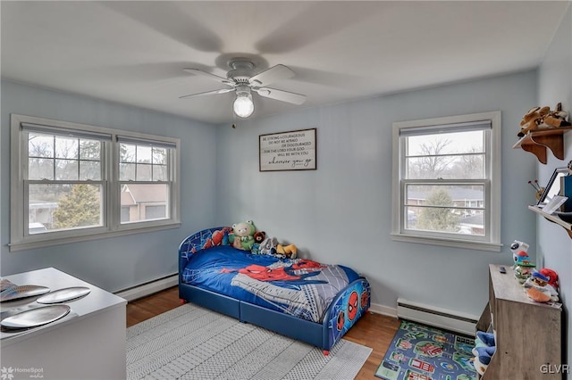 bedroom featuring ceiling fan, a baseboard heating unit, and wood finished floors