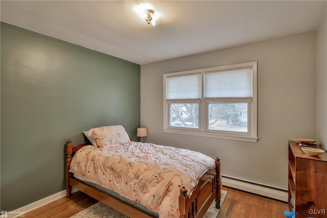 bedroom featuring baseboard heating, wood finished floors, and baseboards