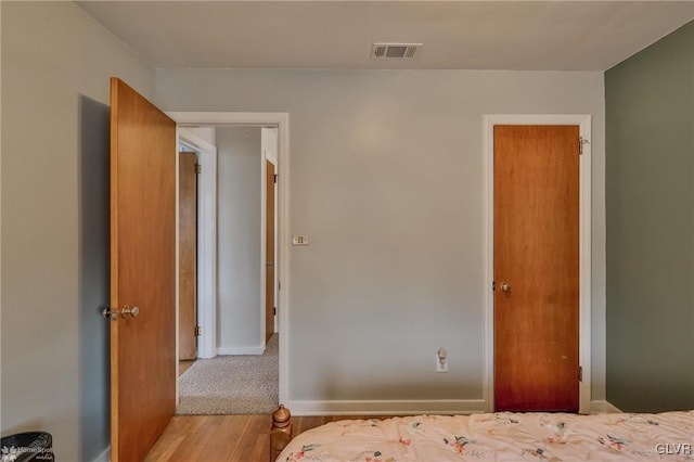 unfurnished bedroom with baseboards, visible vents, and wood finished floors