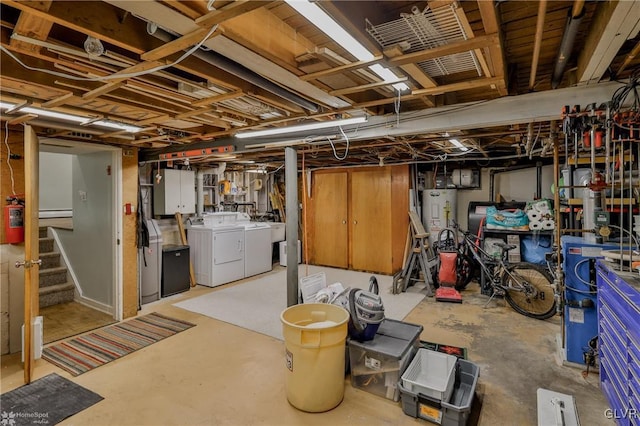 unfinished basement featuring washer and dryer, water heater, and stairway