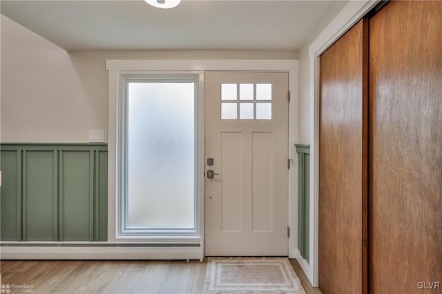 entryway with wainscoting, light wood-style flooring, and a decorative wall