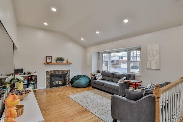 living room featuring light wood-style floors, a fireplace, vaulted ceiling, and recessed lighting