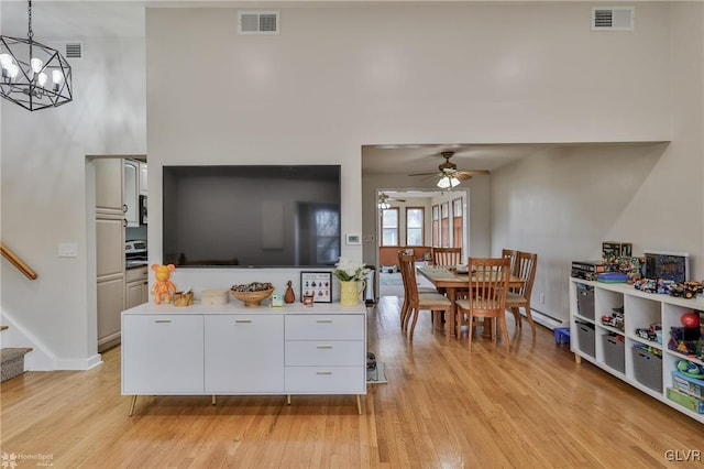 living room with light wood finished floors, a baseboard radiator, visible vents, and stairway